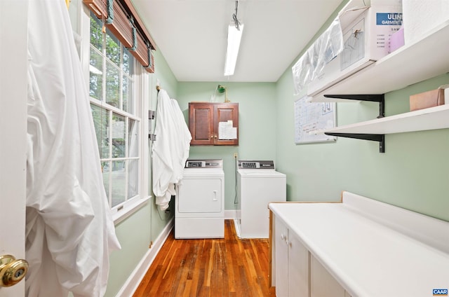 washroom with washing machine and clothes dryer, baseboards, cabinet space, and wood finished floors