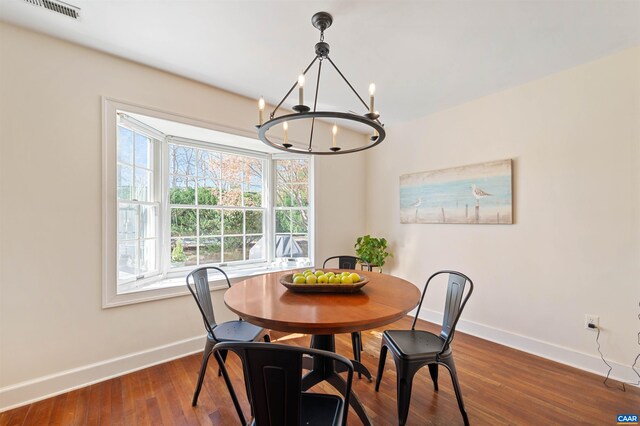 dining area featuring wood finished floors, a chandelier, baseboards, and visible vents