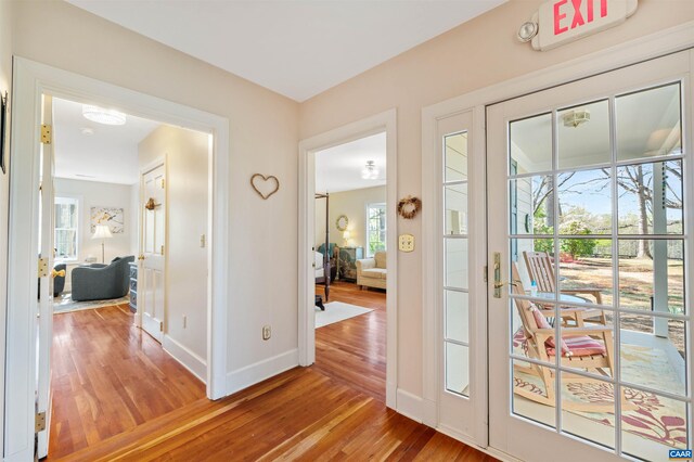 doorway to outside with baseboards, a wealth of natural light, and light wood-style flooring