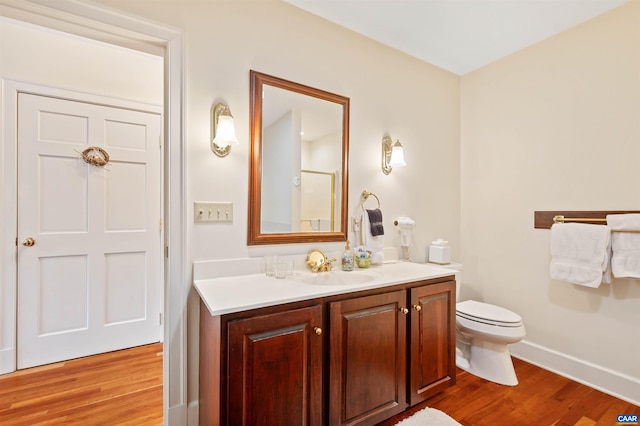bathroom featuring toilet, baseboards, vanity, and wood finished floors