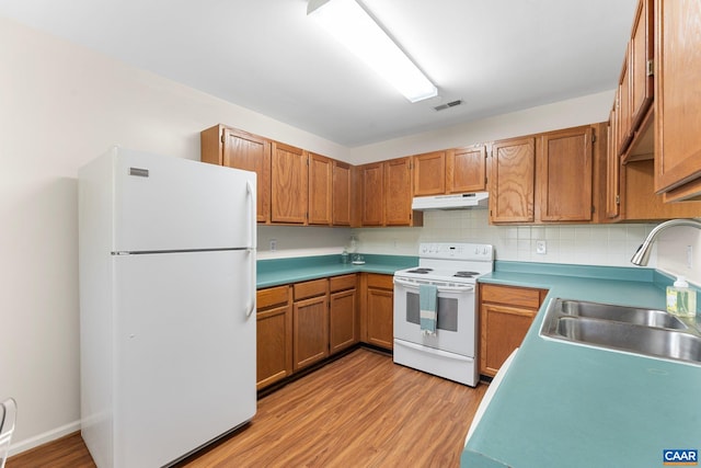 941 Warwick Ct, Charlottesville, VA 22901 - kitchen featuring white appliances, under cabinet range hood, light wood-style floors, brown cabinets, and backsplash