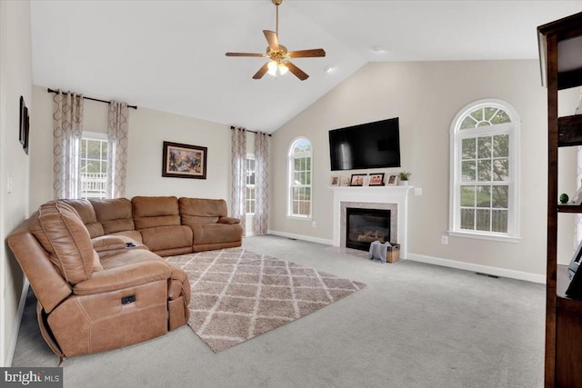 living area featuring a fireplace with flush hearth, carpet, a wealth of natural light, and ceiling fan