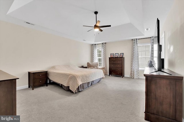 bedroom with visible vents, a raised ceiling, baseboards, and light carpet