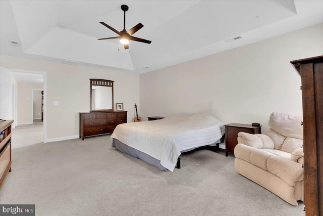 bedroom featuring light colored carpet, a tray ceiling, visible vents, and a ceiling fan