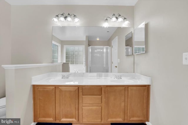 bathroom featuring double vanity, a sink, a stall shower, and toilet
