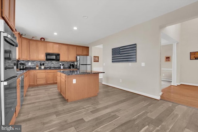 kitchen with decorative backsplash, stainless steel appliances, light wood-style floors, a kitchen island, and recessed lighting