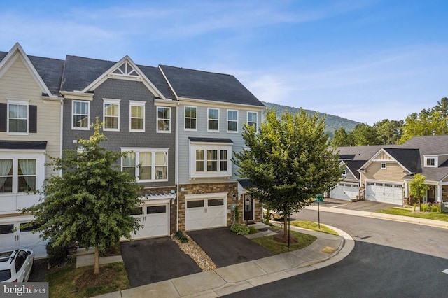 townhome / multi-family property featuring driveway, an attached garage, and stone siding