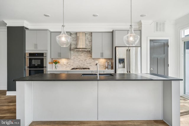 kitchen with wall chimney exhaust hood, stainless steel appliances, a sink, gray cabinets, and dark countertops