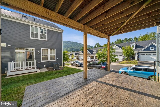 wooden deck featuring central air condition unit, a residential view, a mountain view, and a lawn