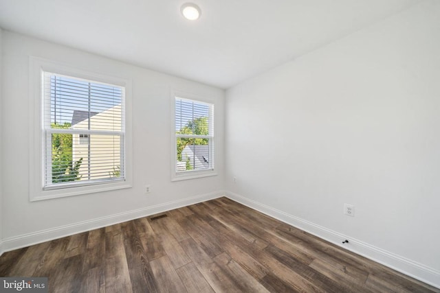 unfurnished room with dark wood finished floors and baseboards