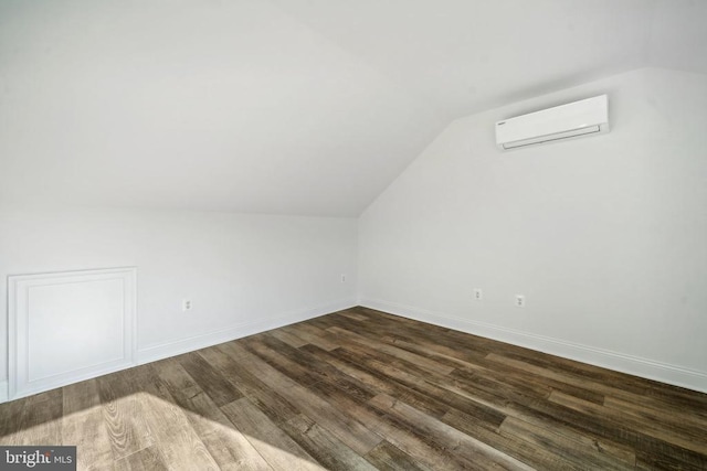 bonus room with a wall unit AC, lofted ceiling, dark wood-style flooring, and baseboards