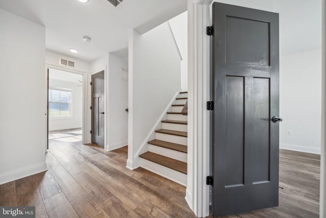 stairway with baseboards, wood finished floors, and recessed lighting
