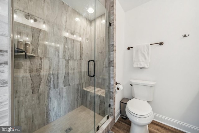 full bathroom with a shower stall, baseboards, toilet, and wood finished floors