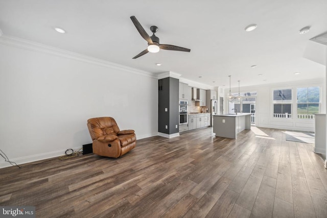unfurnished living room featuring a ceiling fan, dark wood-style floors, recessed lighting, ornamental molding, and baseboards