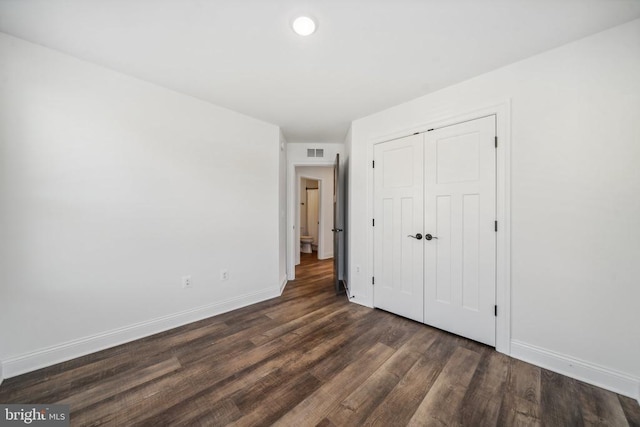 unfurnished bedroom featuring baseboards, dark wood-style flooring, and a closet