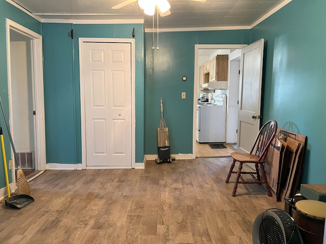 interior space with crown molding, visible vents, wood finished floors, washer / dryer, and baseboards