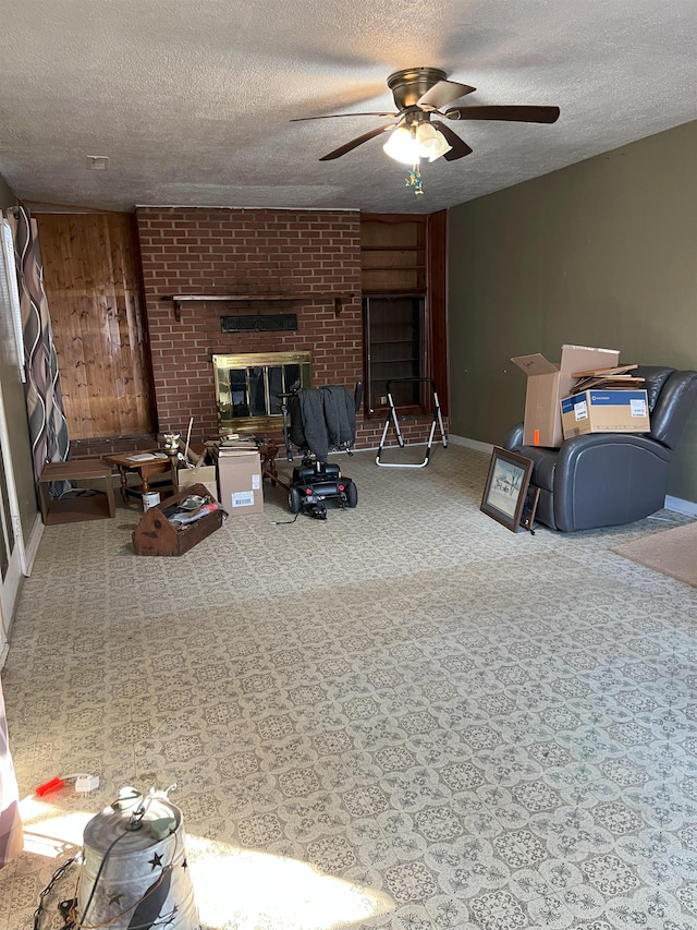 living area with baseboards, a ceiling fan, a textured ceiling, carpet flooring, and a brick fireplace