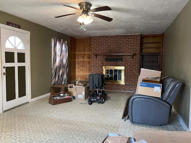 living room with carpet, a brick fireplace, ceiling fan, a textured ceiling, and baseboards