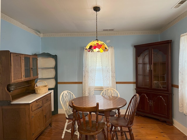 dining area featuring visible vents, crown molding, baseboards, and wood finished floors