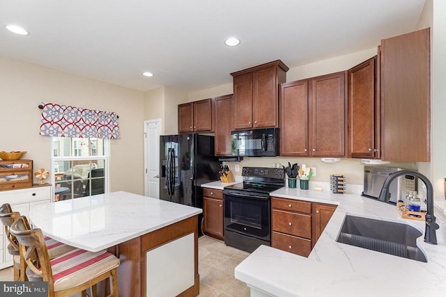  - kitchen featuring black appliances, recessed lighting, a breakfast bar area, light stone counters, and a center island
