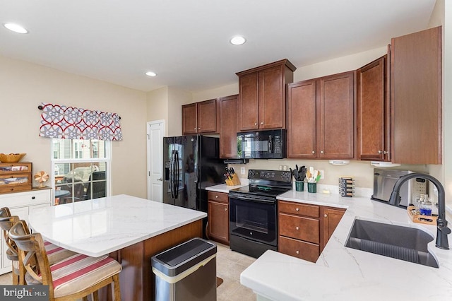  - kitchen featuring black appliances, recessed lighting, light stone countertops, a breakfast bar, and a kitchen island