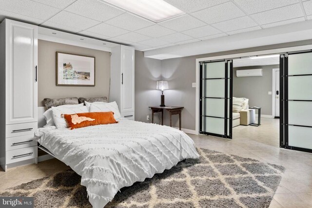 325 Oneals Rd, Madison, VA 22727 - bedroom with a wall unit AC, light tile patterned floors, a drop ceiling, baseboards, and a barn door