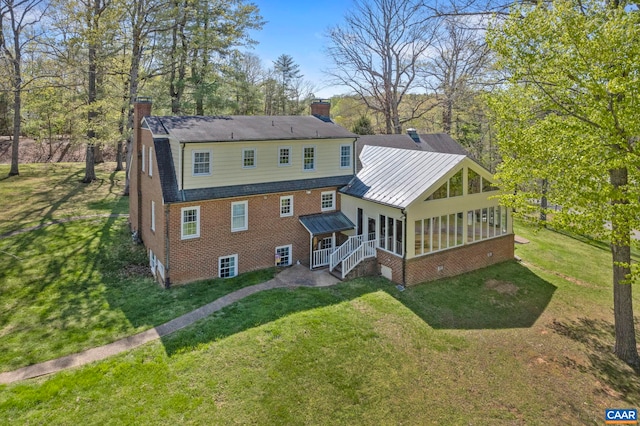 330 Carrsbrook Dr, Charlottesville, VA 22901 - back of property featuring a sunroom, a chimney, a standing seam roof, brick siding, and a lawn