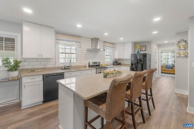 330 Carrsbrook Dr, Charlottesville, VA 22901 - kitchen featuring black appliances, wall chimney range hood, a kitchen breakfast bar, tasteful backsplash, and white cabinetry