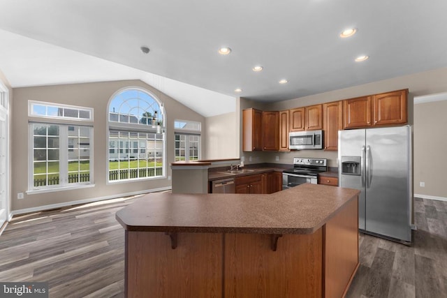 12190 Remland Ct, Remington, VA 22734 - kitchen featuring appliances with stainless steel finishes, lofted ceiling, dark countertops, wood finished floors, and a breakfast bar area