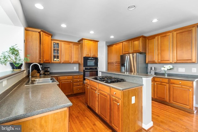 9016 Laurel Oak Ln, Fredericksburg, VA 22407 - kitchen featuring black appliances, a sink, brown cabinetry, a kitchen island, and light wood-style flooring