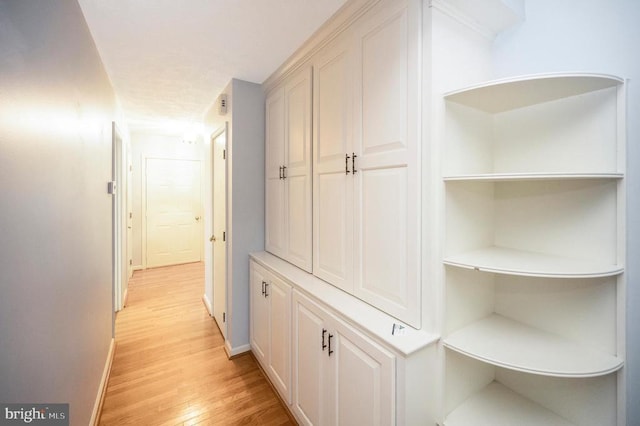 corridor with light wood-type flooring and baseboards