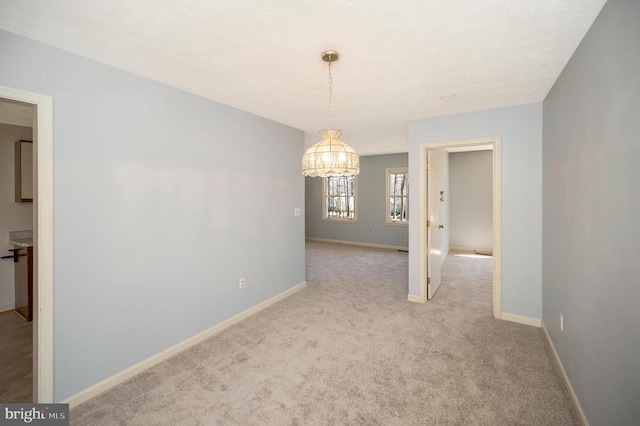 unfurnished dining area featuring an inviting chandelier, baseboards, and carpet
