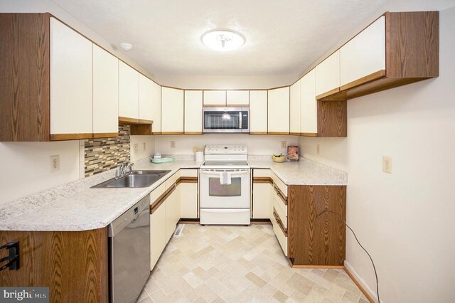 kitchen with light countertops, white cabinets, appliances with stainless steel finishes, and a sink