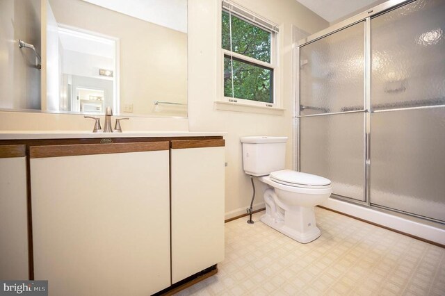 full bath with a shower stall, baseboards, vanity, and toilet