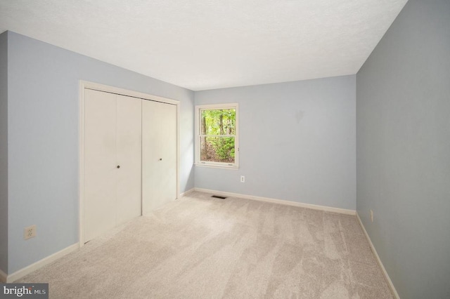 unfurnished bedroom with baseboards, carpet flooring, a closet, and visible vents