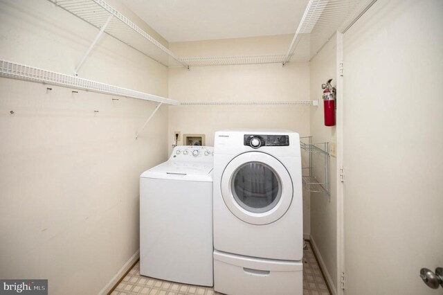 laundry area featuring washer and clothes dryer, laundry area, light floors, and baseboards