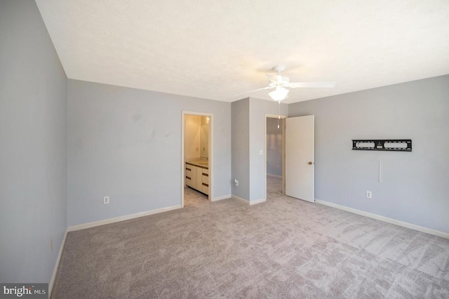 unfurnished bedroom featuring light colored carpet, ensuite bathroom, and baseboards