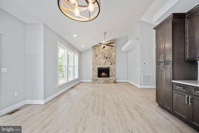 79 Hickory Cir, Mineral, VA 23117 - unfurnished living room with light wood-style flooring, a chandelier, a stone fireplace, vaulted ceiling, and a ceiling fan