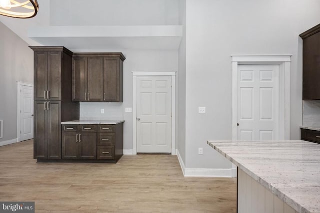 79 Hickory Cir, Mineral, VA 23117 - kitchen with dark brown cabinets, light wood finished floors, light stone countertops, a high ceiling, and decorative backsplash