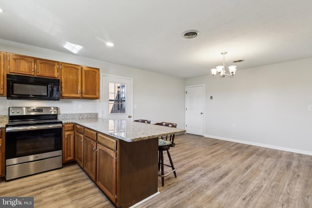 kitchen with a breakfast bar, stainless steel range with electric stovetop, decorative light fixtures, light hardwood / wood-style floors, and kitchen peninsula