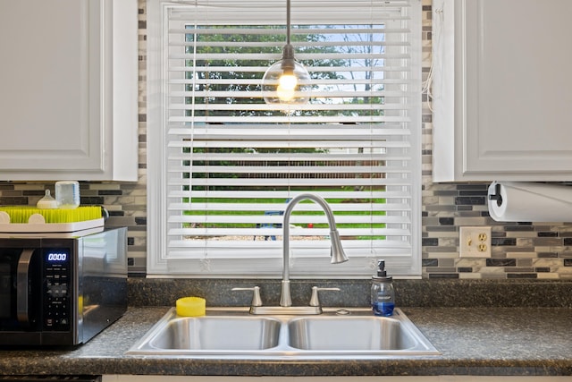 701 Horseshoe Cir, Stuarts Draft, VA 24477 - kitchen view of a sink, dark countertops, backsplash, white cabinetry, and hanging light fixtures