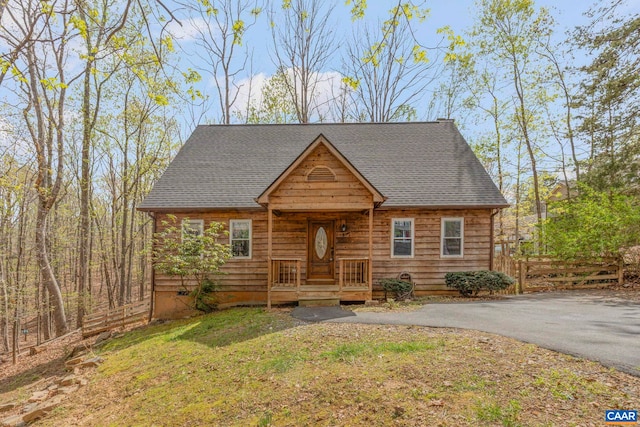 view of front of property featuring roof with shingles, a front yard, and driveway