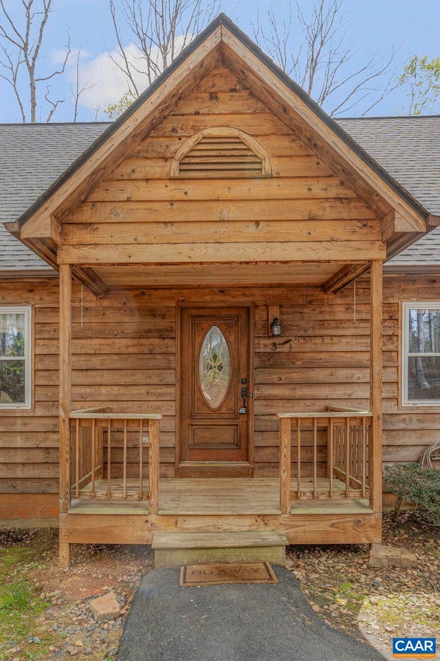 doorway to property with roof with shingles