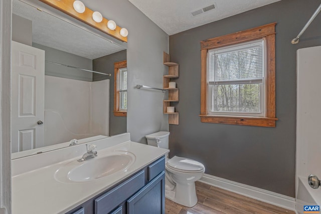 full bath with baseboards, toilet, wood finished floors, vanity, and shower / tub combination