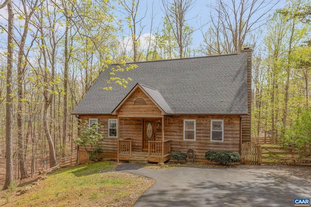 view of front of property with roof with shingles and fence