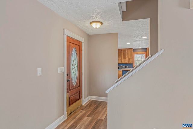 entrance foyer featuring baseboards, wood finished floors, a textured ceiling, and recessed lighting