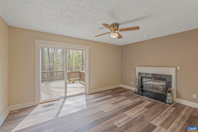 unfurnished living room featuring a ceiling fan, wood finished floors, a premium fireplace, a textured ceiling, and baseboards