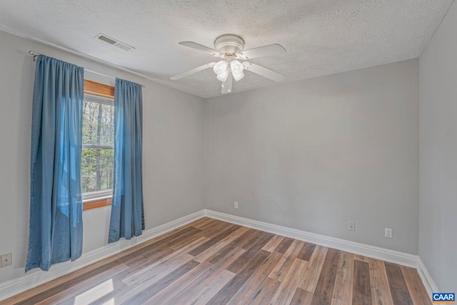 spare room featuring wood finished floors, a textured ceiling, baseboards, and ceiling fan