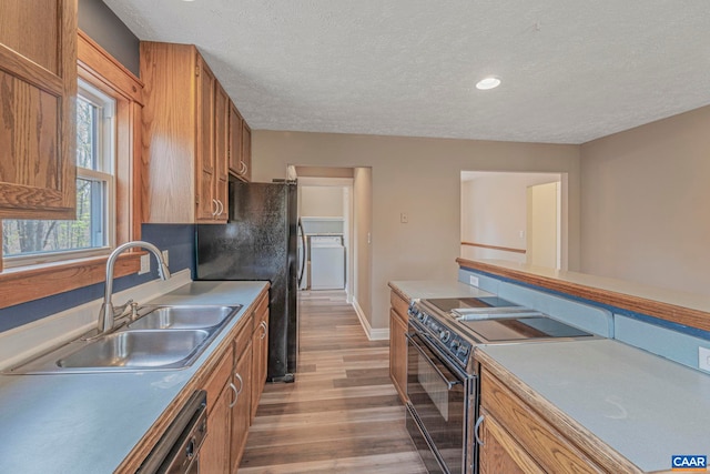 kitchen featuring a sink, black appliances, a textured ceiling, light wood-type flooring, and brown cabinets