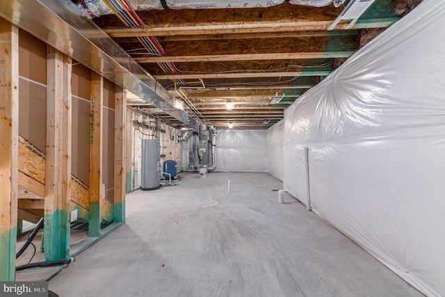 unfinished below grade area featuring water heater and a water pressure tank